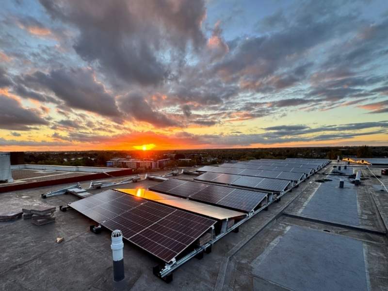 Solaranlage in Düsseldorf: mehrere Solarpaneelen auf einem Dach während des Sonnenuntergangs. Der Himmel leuchtet in Orange Tönen.
