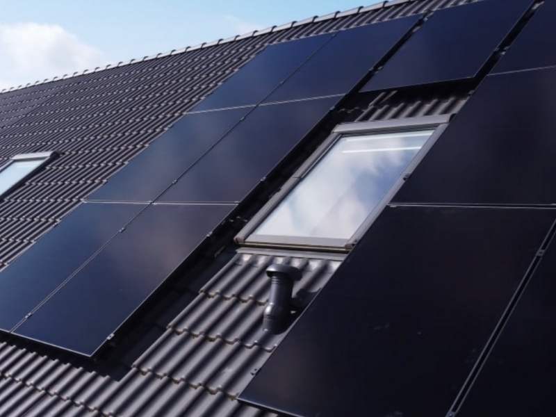 Eine Nahaufnahme von Solarpaneelen um ein Dachfenster herum.